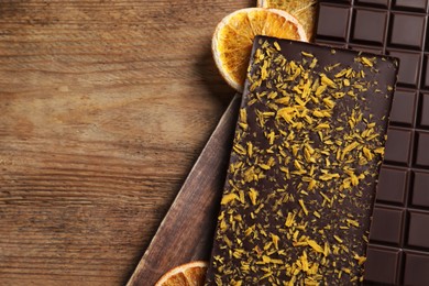 Photo of Chocolate bars with freeze dried orange on wooden table, top view. Space for text