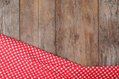 Photo of Checkered picnic blanket on wooden background, top view. Space for text