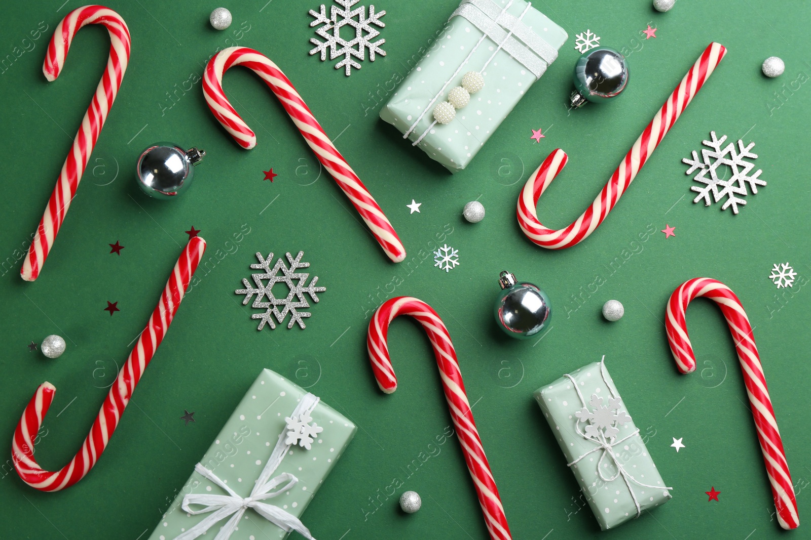 Photo of Flat lay composition with candy canes and Christmas decor on green background