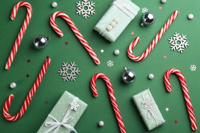 Flat lay composition with candy canes and Christmas decor on green background