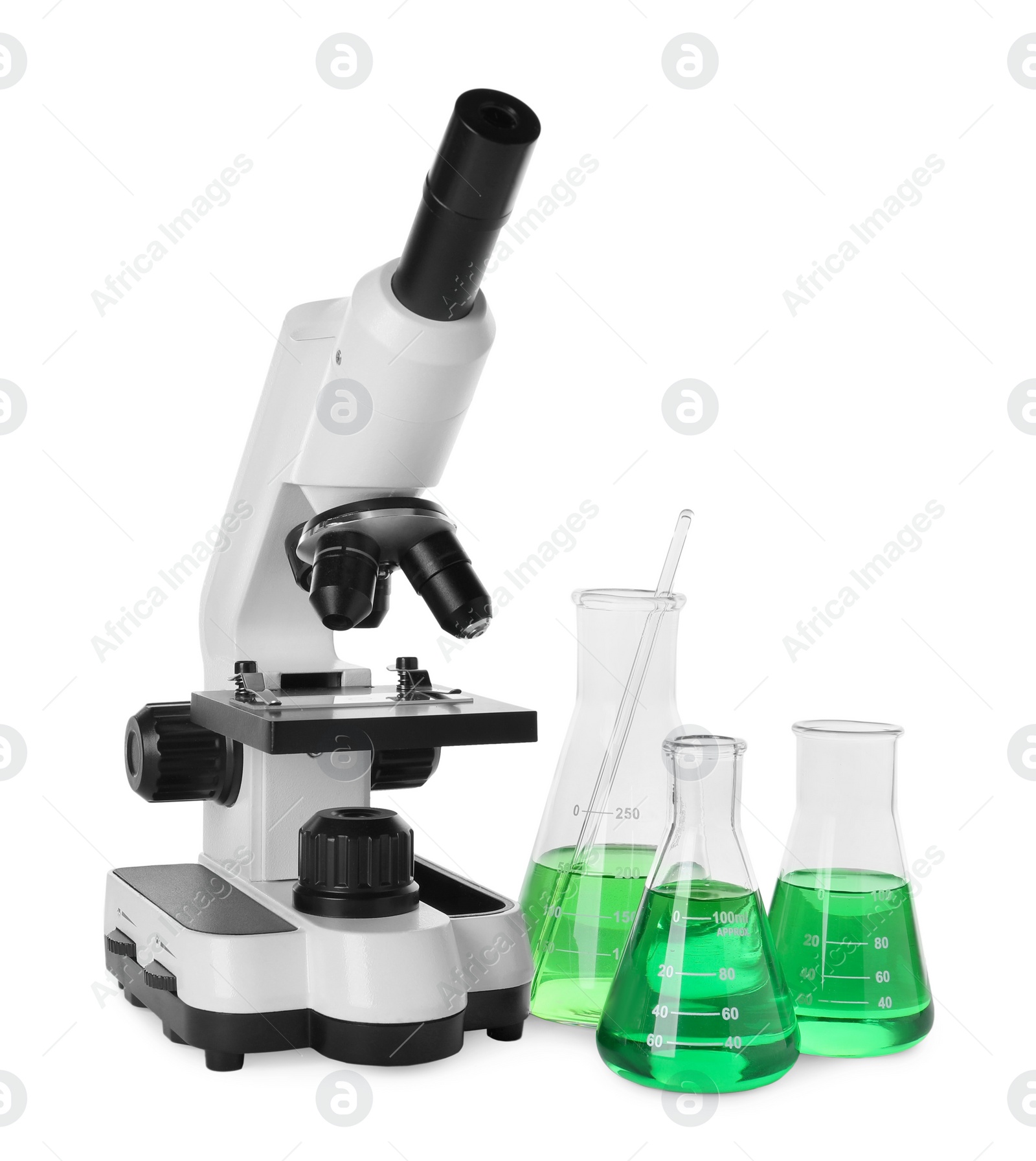 Photo of Laboratory glassware with green liquid and microscope isolated on white