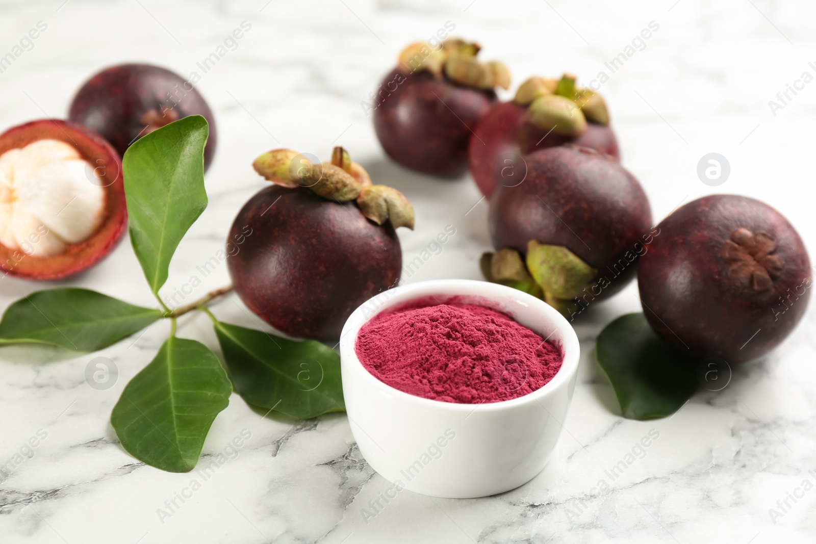 Photo of Purple mangosteen powder and fruits on white marble table