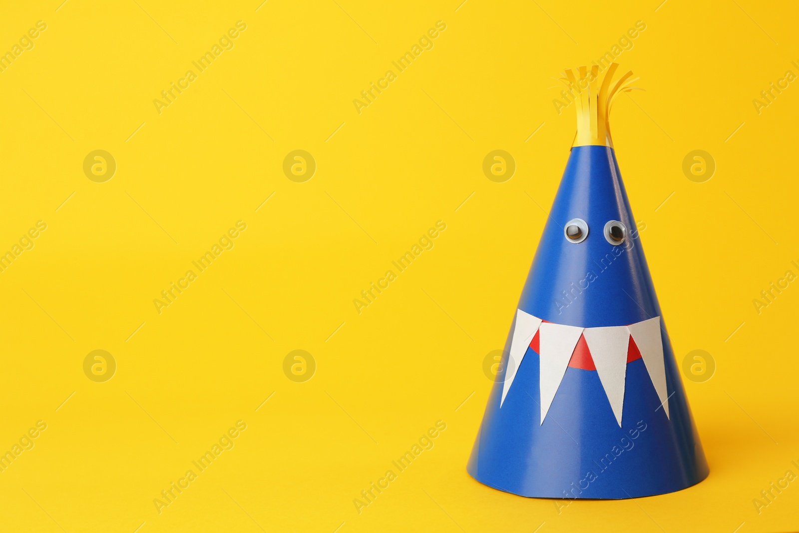 Photo of Funny blue monster on yellow background, space for text. Halloween decoration