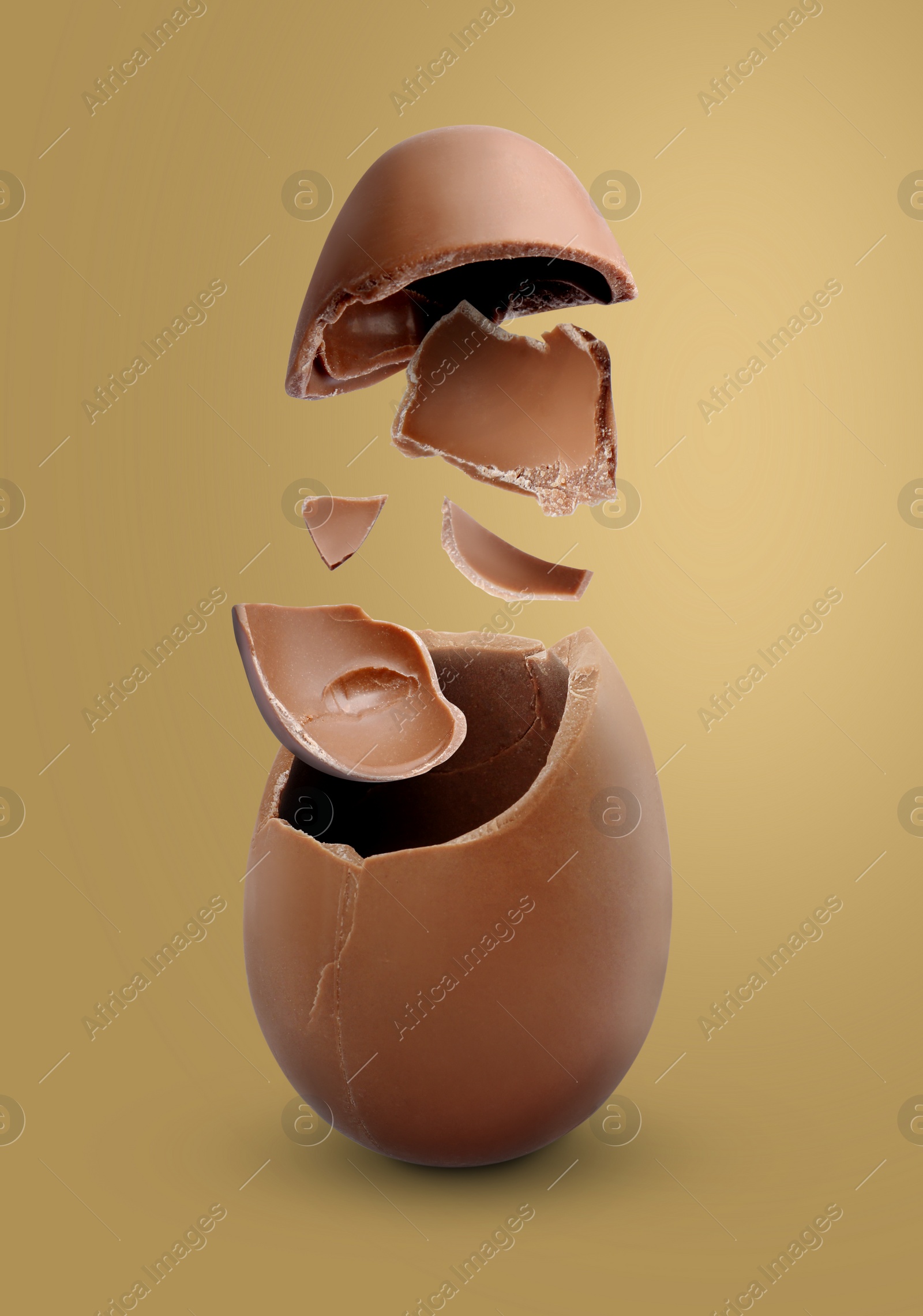 Image of Exploded milk chocolate egg on dark gold background