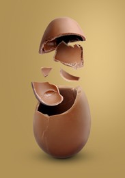 Exploded milk chocolate egg on dark gold background