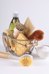 Photo of Set of different cleaning supplies in basket on white background