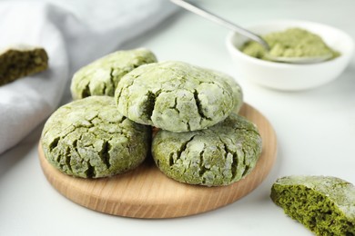 Photo of Board with tasty matcha cookies on white table, closeup
