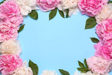 Photo of Frame made of beautiful peony flowers and green leaves on light blue background, flat lay. Space for text