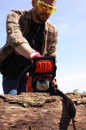 Photo of Man sawing wooden log on sunny day, low angle view