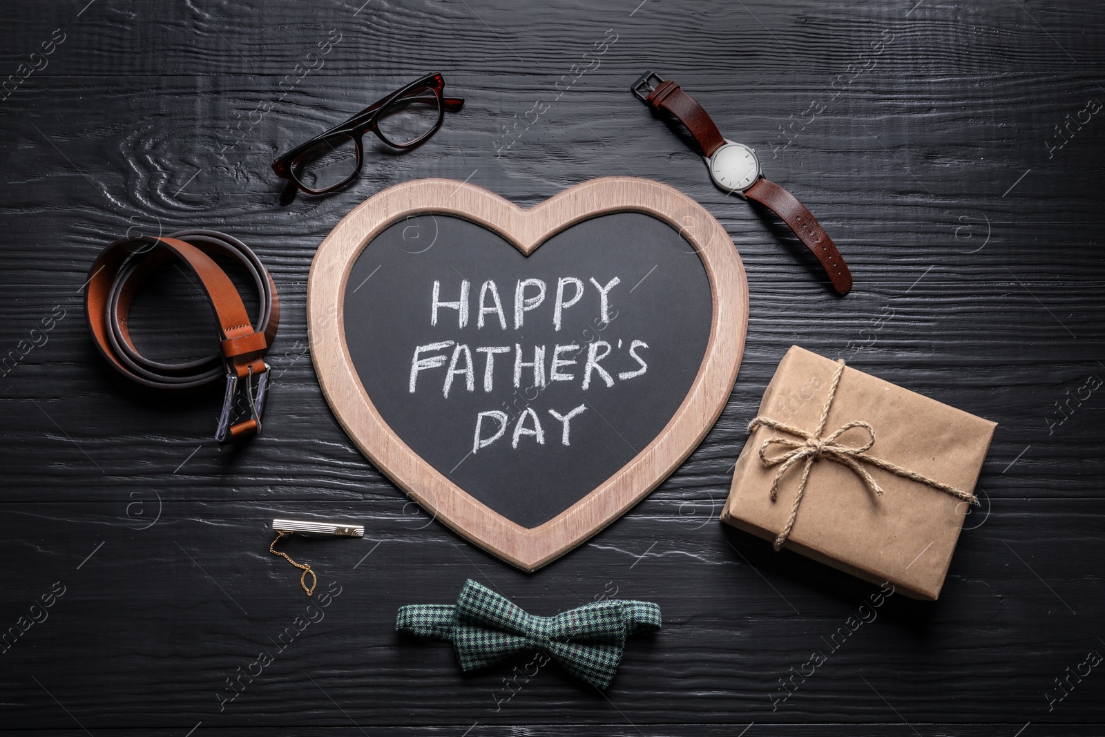 Photo of Chalkboard with words HAPPY FATHER'S DAY and different gifts on wooden background, top view
