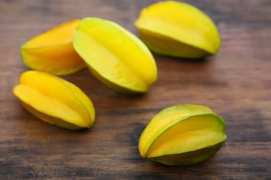 Photo of Many delicious ripe carambolas on wooden table