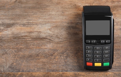 Photo of Modern payment terminal on wooden background, top view. Space for text
