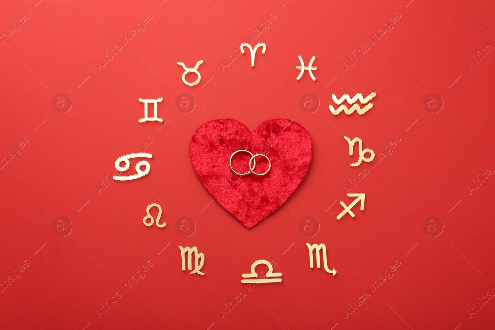 Photo of Zodiac signs, heart and wedding rings on red background, flat lay