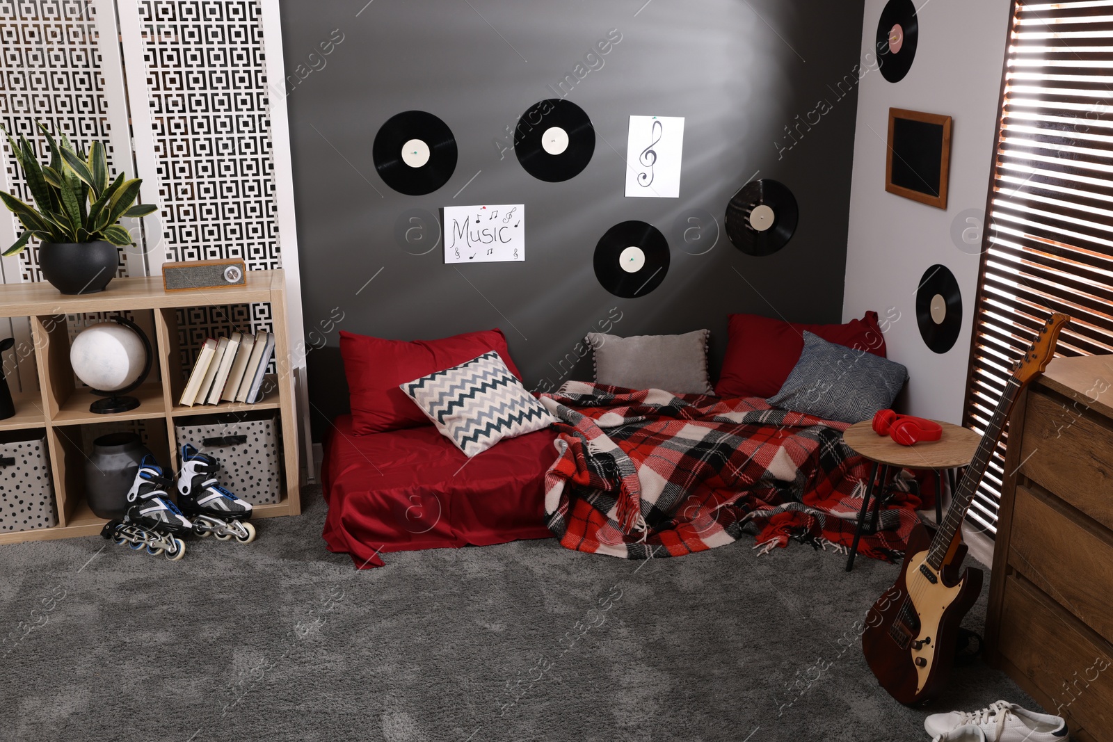 Photo of Stylish teenager's room with bed, guitar and vinyl records on wall. Interior design