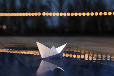 Photo of White paper boat in puddle on street