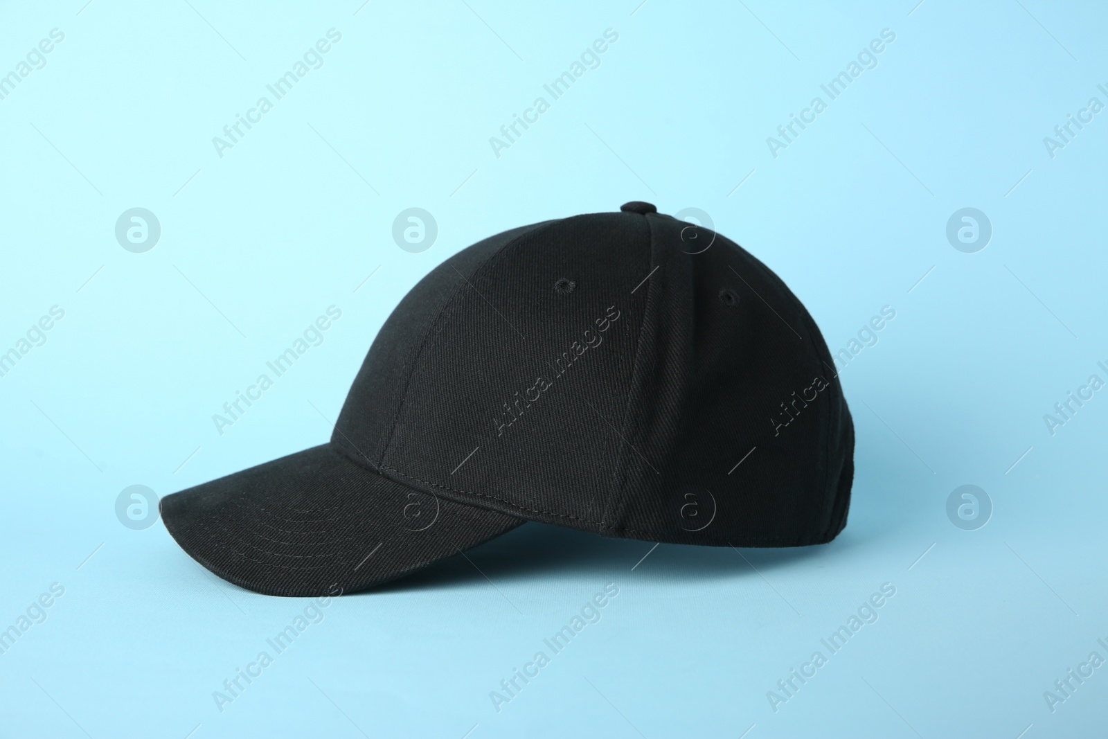 Photo of Stylish black baseball cap on light blue background