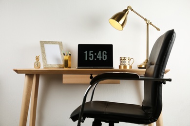 Photo of Modern workplace with laptop and golden decor on desk near wall. Stylish interior design