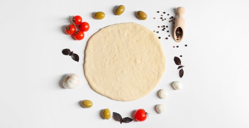 Fresh pizza dough and products on white background, flat lay