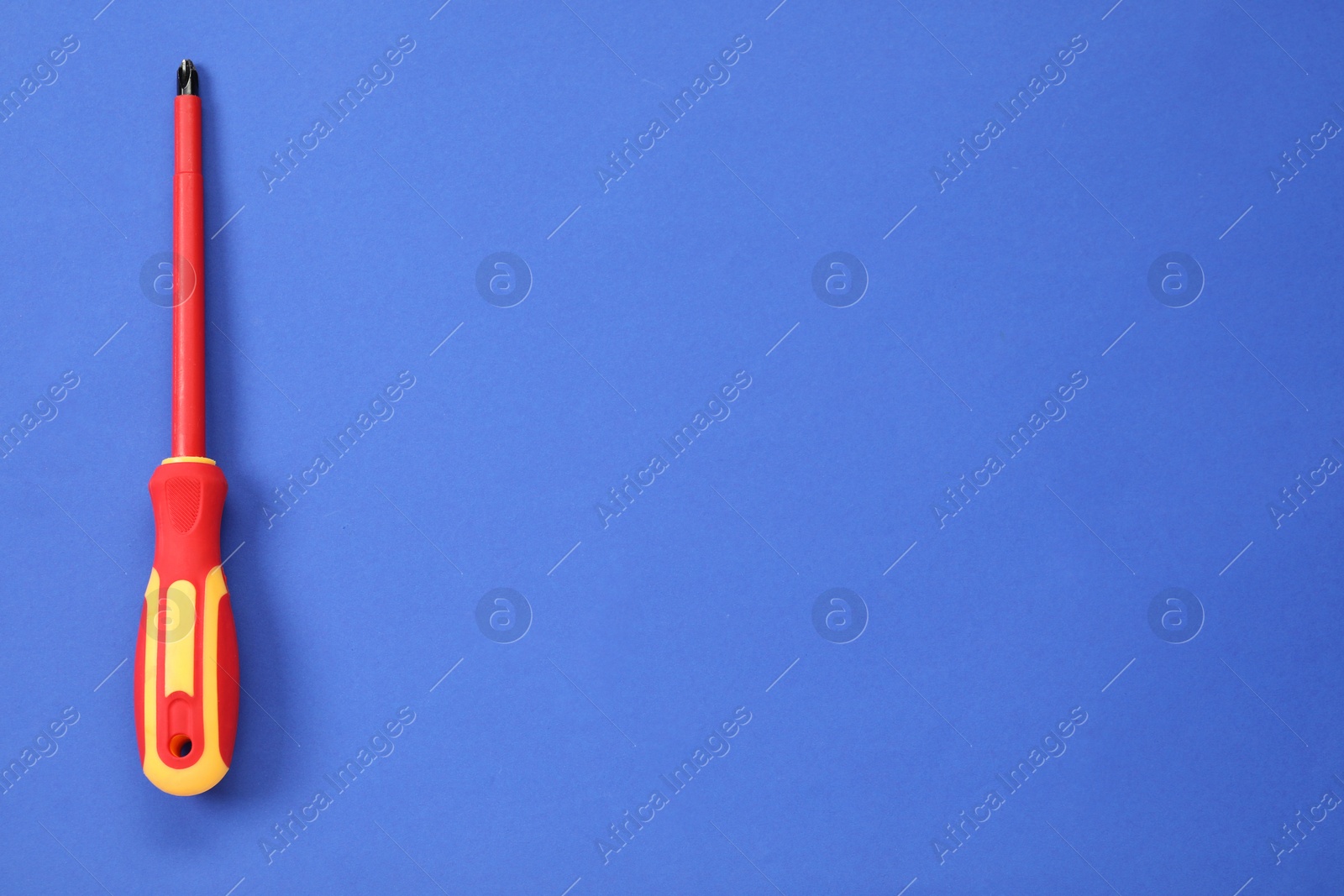 Photo of Screwdriver with red handle on blue background, top view. Space for text