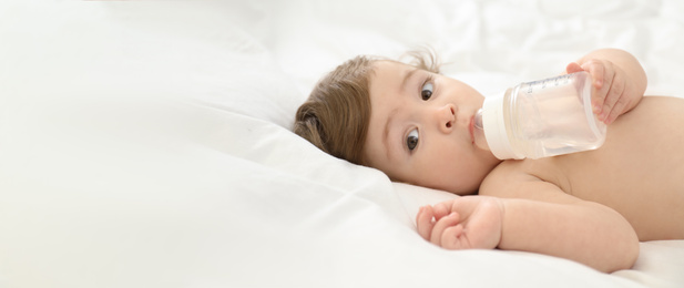 Image of Cute little baby with bottle on bed, space for text. Banner design