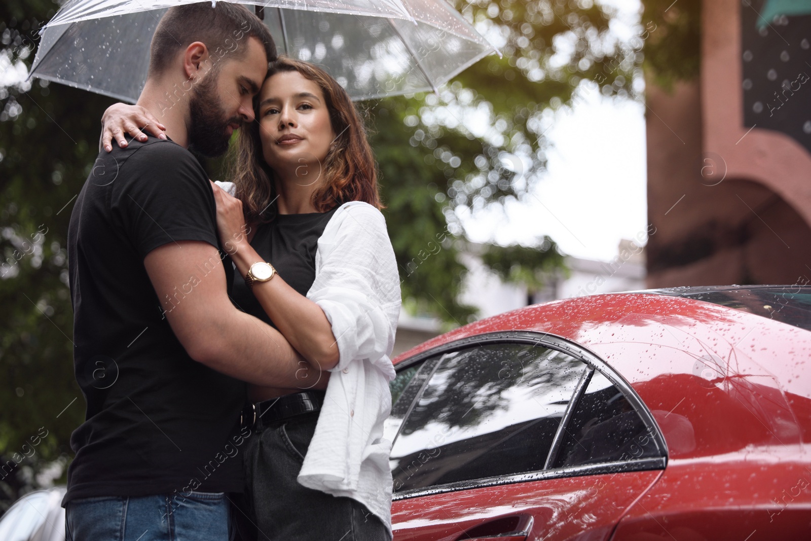 Photo of Young couple with umbrella enjoying time together under rain on city street, space for text