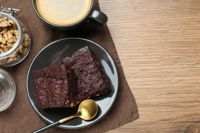 Photo of Delicious chocolate brownies with nuts and coffee on wooden table, flat lay. Space for text