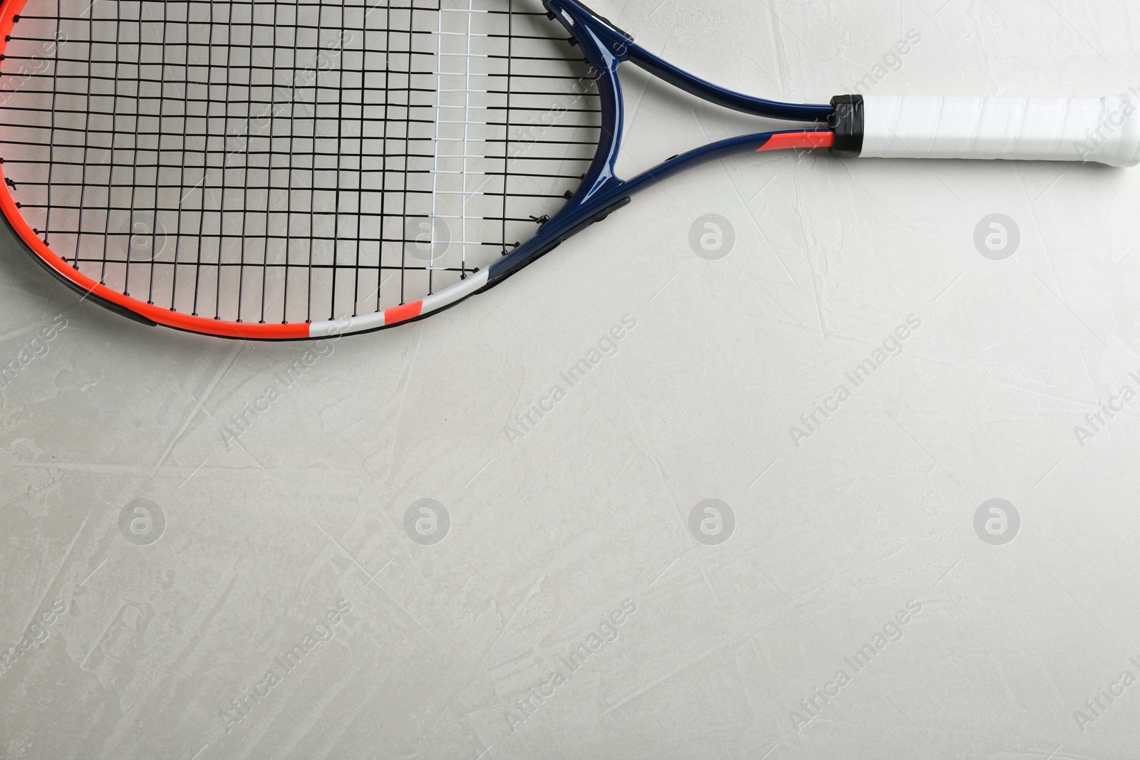Photo of Tennis racket on grey table, top view. Space for text