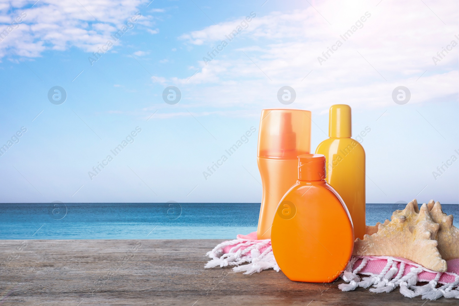 Image of Set of sun protection products on wooden table near sea. Space for text