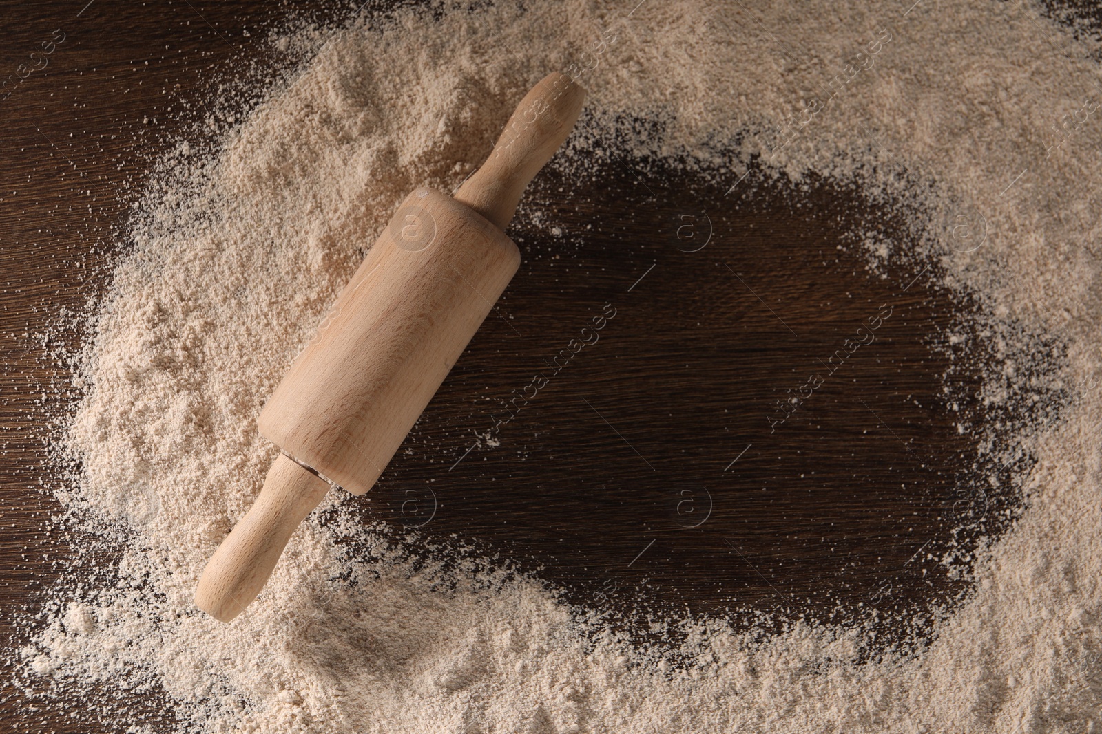 Photo of Frame of flour and rolling pin on wooden table, top view. Space for text