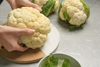 Photo of Woman with fresh cauliflower at light grey table, closeup