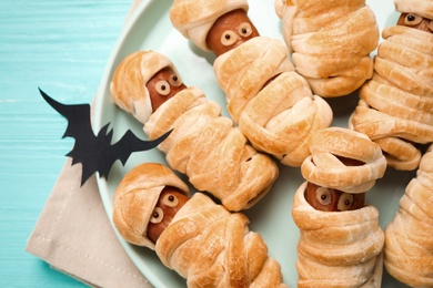 Spooky sausage mummies served on blue table, closeup. Halloween treat