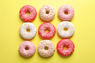 Photo of Delicious glazed doughnuts on color background, top view