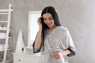 Photo of Beautiful young woman wearing silk robe in bathroom