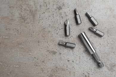 Photo of Different drill bits on grey table, flat lay. Space for text