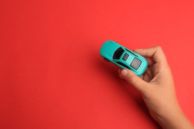 Photo of Child holding toy car on red background, top view. Space for text
