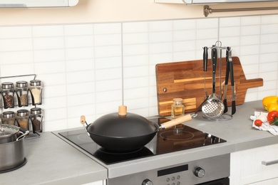 Photo of Set of clean cookware, utensils and products on table in modern kitchen