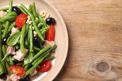 Photo of Plate of tasty salad with green beans on wooden table, top view. Space for text