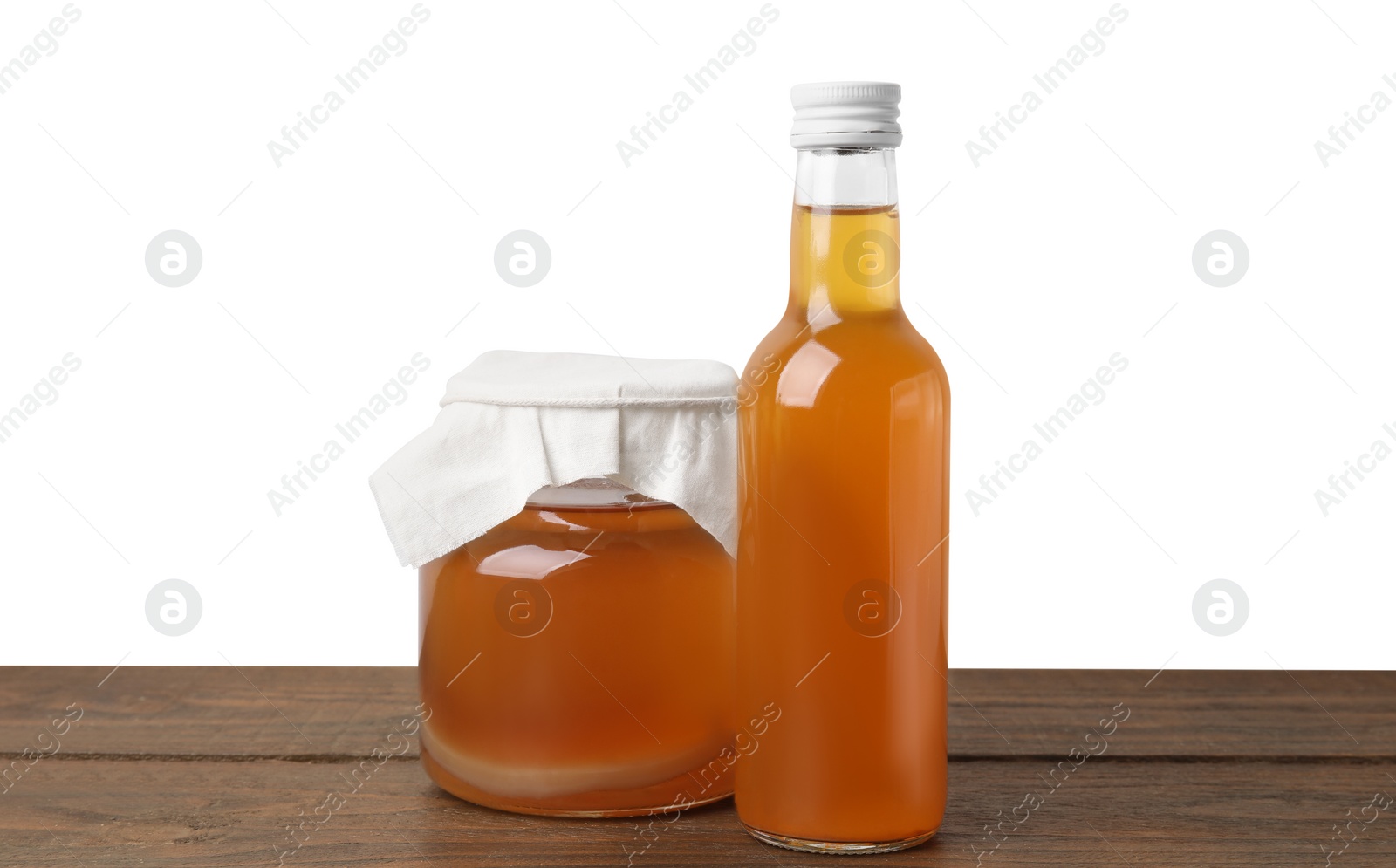 Photo of Delicious kombucha in glass bottle and jar on wooden table against white background