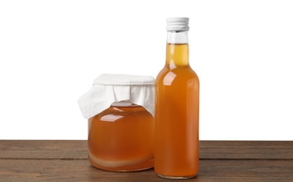 Photo of Delicious kombucha in glass bottle and jar on wooden table against white background