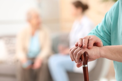 Photo of Closeup view of elderly man with cane in nursing home, space for text. Assisting senior generation