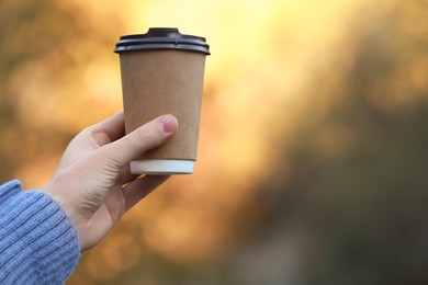 Photo of Woman holding takeaway coffee cup outdoors, closeup. Space for text