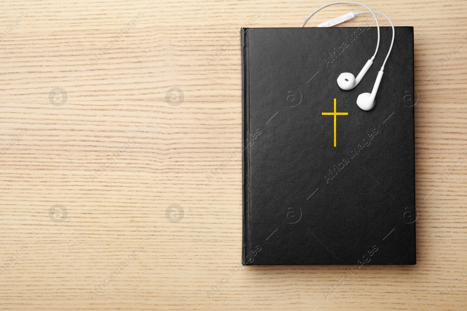 Photo of Bible and earphones on wooden background, top view with space for text. Religious audiobook