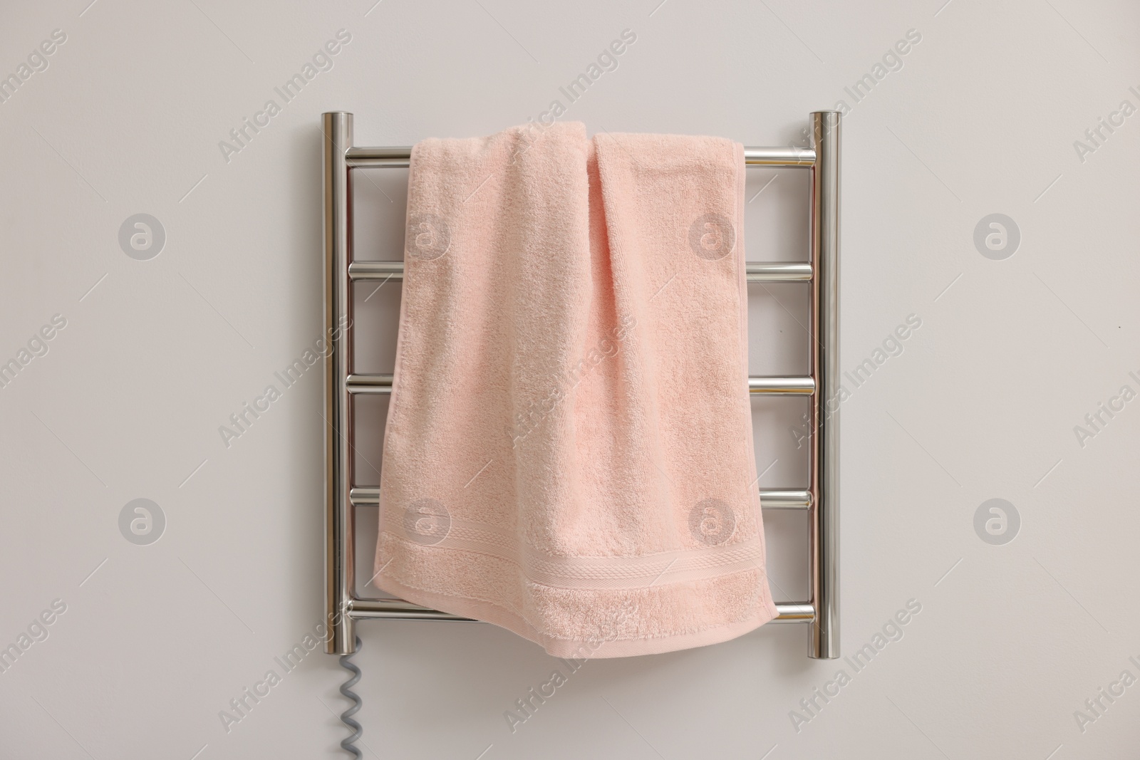 Photo of Heated rail with pink towel on white wall