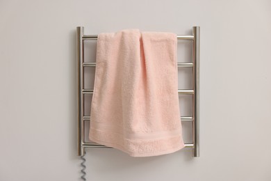 Photo of Heated rail with pink towel on white wall