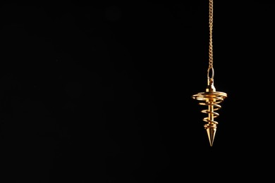 Photo of Beautiful golden pendulum with chain on black background, space for text. Hypnosis session