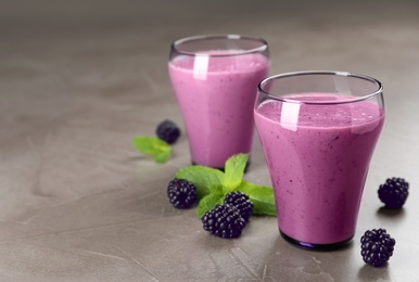 Photo of Glasses with blackberry yogurt smoothies on grey table