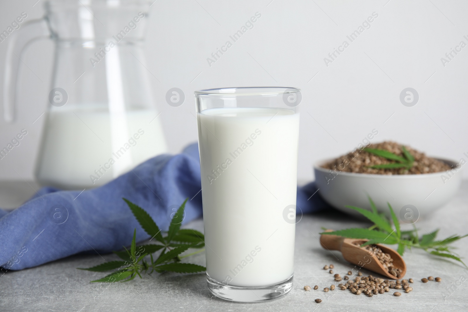 Photo of Hemp milk, seeds and fresh leaves on light grey table