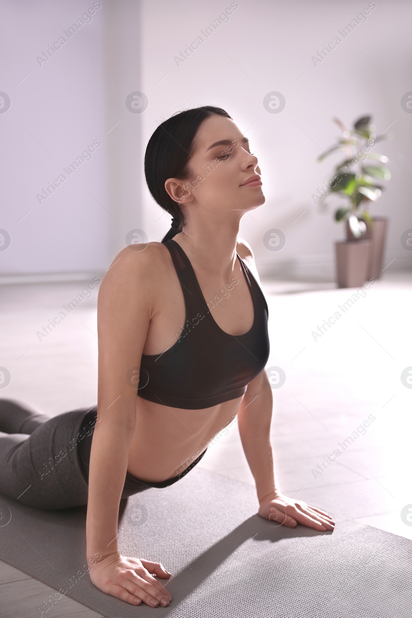 Photo of Young woman practicing cobra asana in yoga studio. Bhujangasana pose