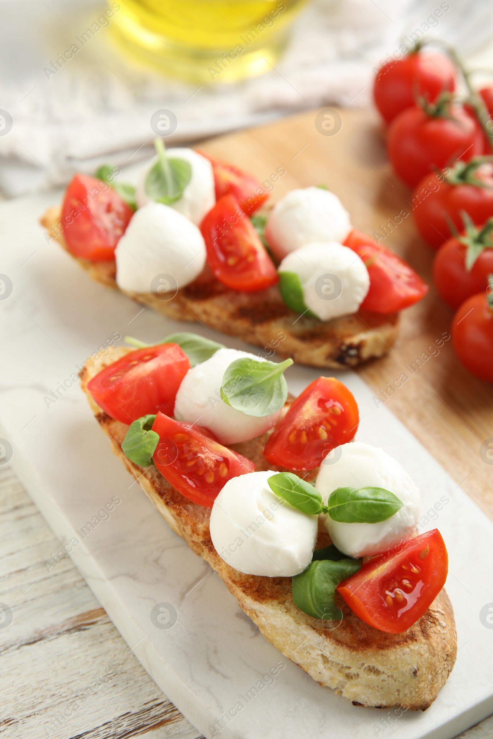 Photo of Delicious sandwiches with mozzarella, fresh tomatoes and basil on board