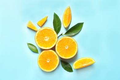 Fresh oranges and leaves on color background, flat lay. Citrus fruits